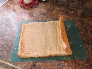 This is why you roll it in the first place - so it cools being used to being rolls, and you don't break it rolling a cake that cooled flat.